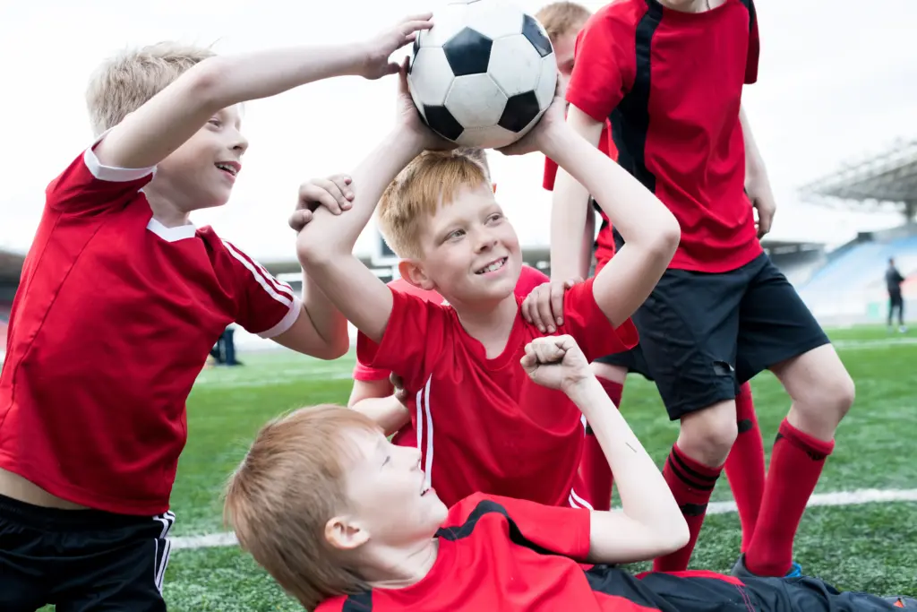 Junge Fußballspieler im roten Trikot jubeln mit einem Ball beim Training von Marcel Bodien in Lübeck