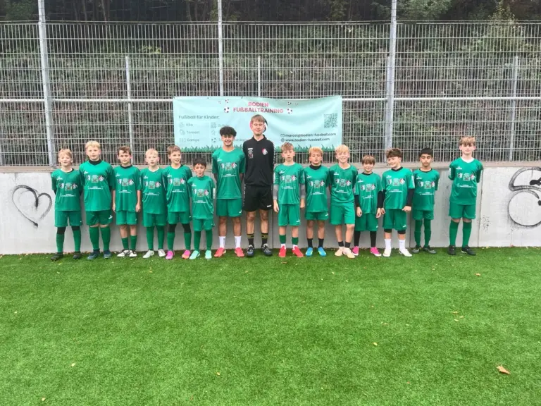 Gruppenfoto einer Trainingsgruppe mit Trainer vor dem Banner von Bodien Fußballtraining