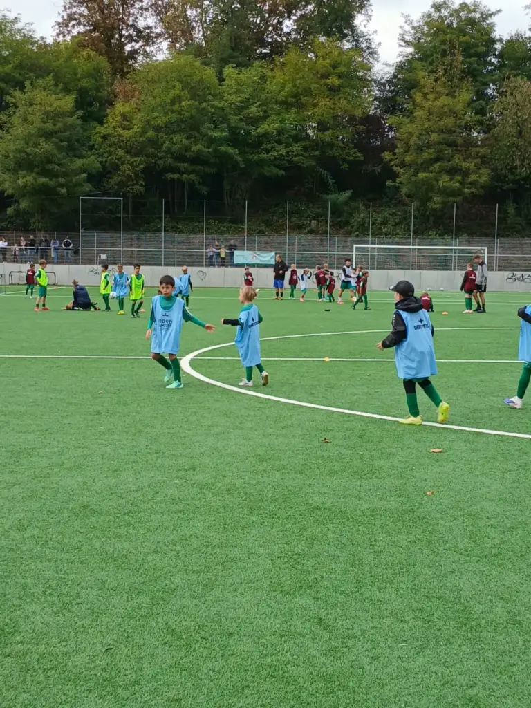 Kinder in blauen Leibchen spielen ein Trainingsspiel auf dem Kunstrasenplatz in Schwalbach