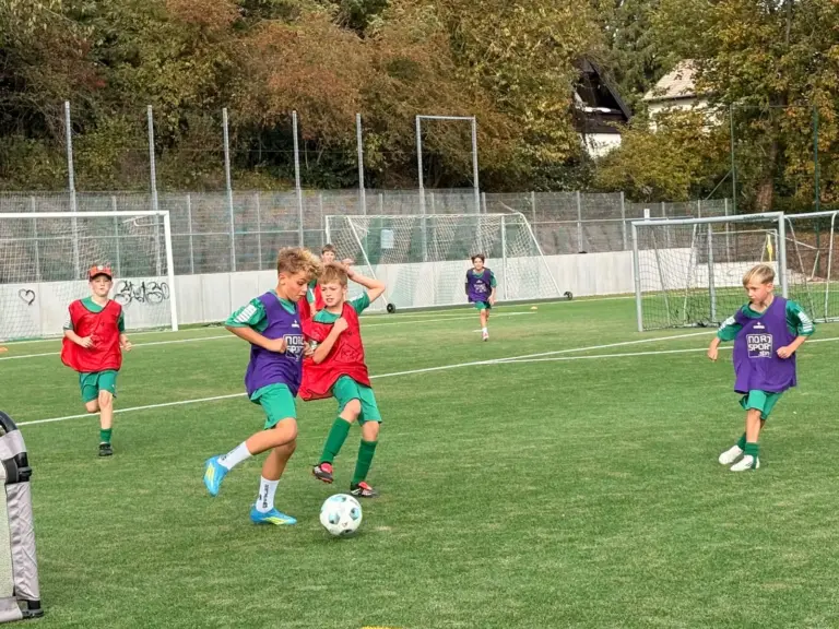 Kinder in Leibchen kämpfen beim Trainingsspiel im Fußballcamp Herbst 2026 in Schwalbach um den Ball